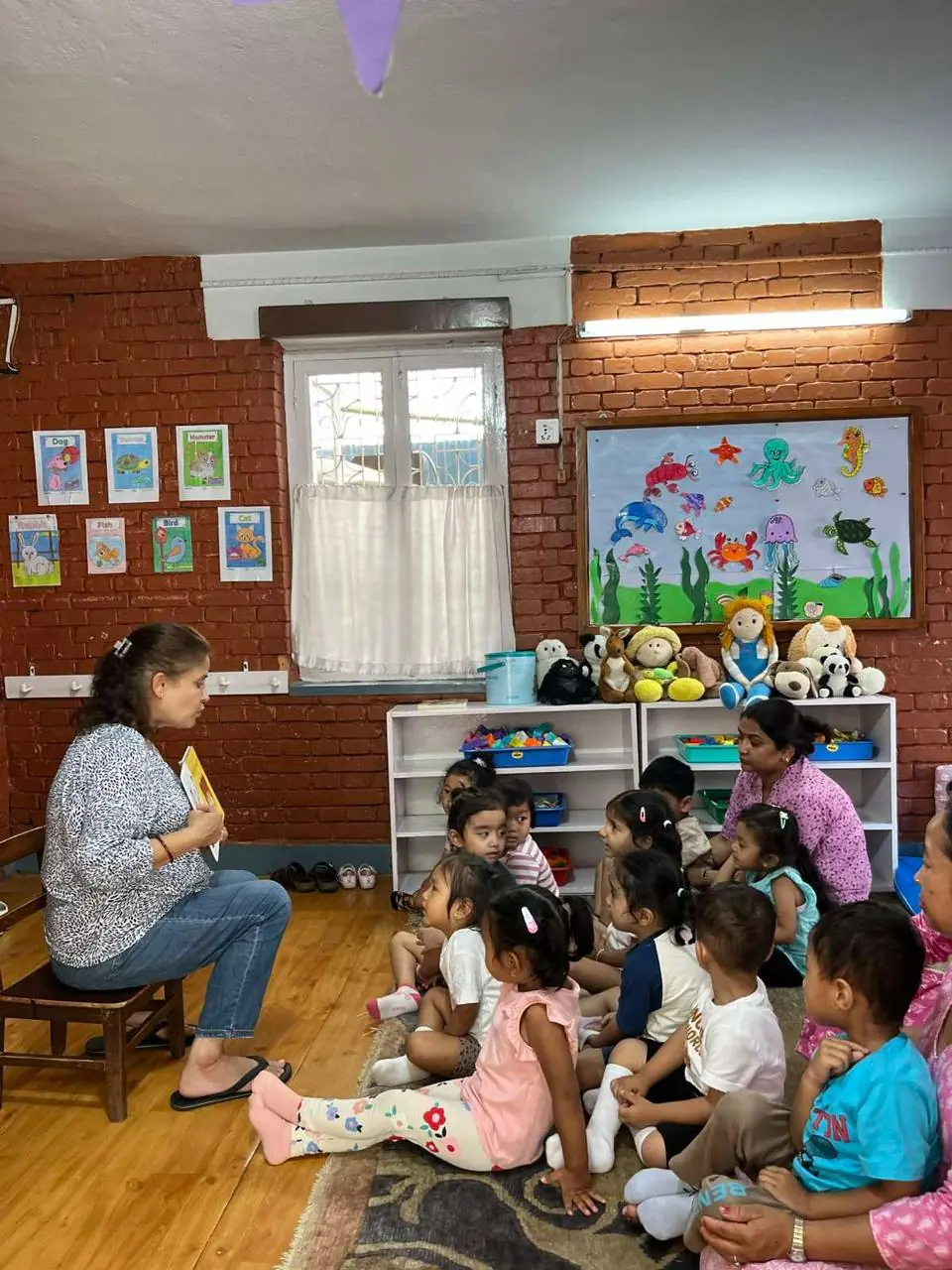A teacher reading a book to the children.